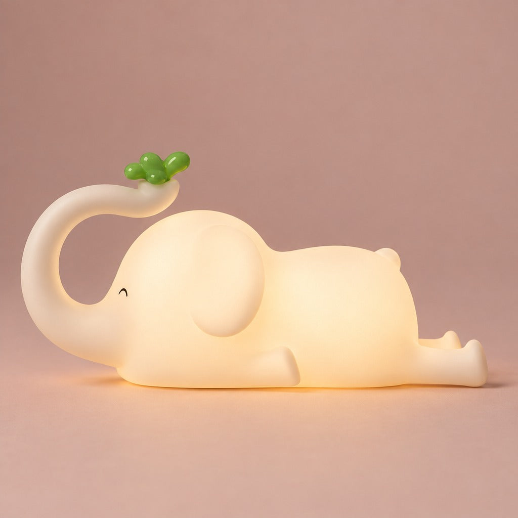 White elephant night light with green sprout on its trunk, glowing warm