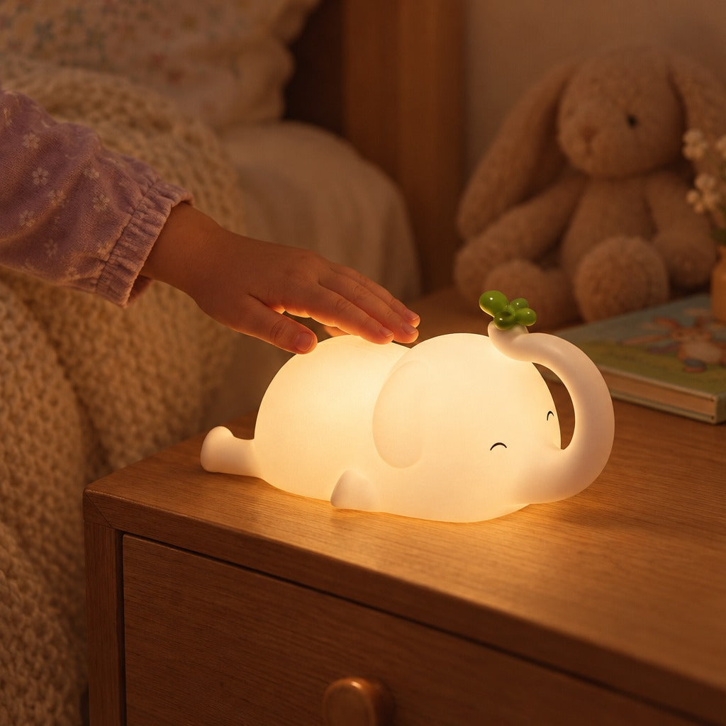 Child's hand patting the glowing elephant night light on a bedside table