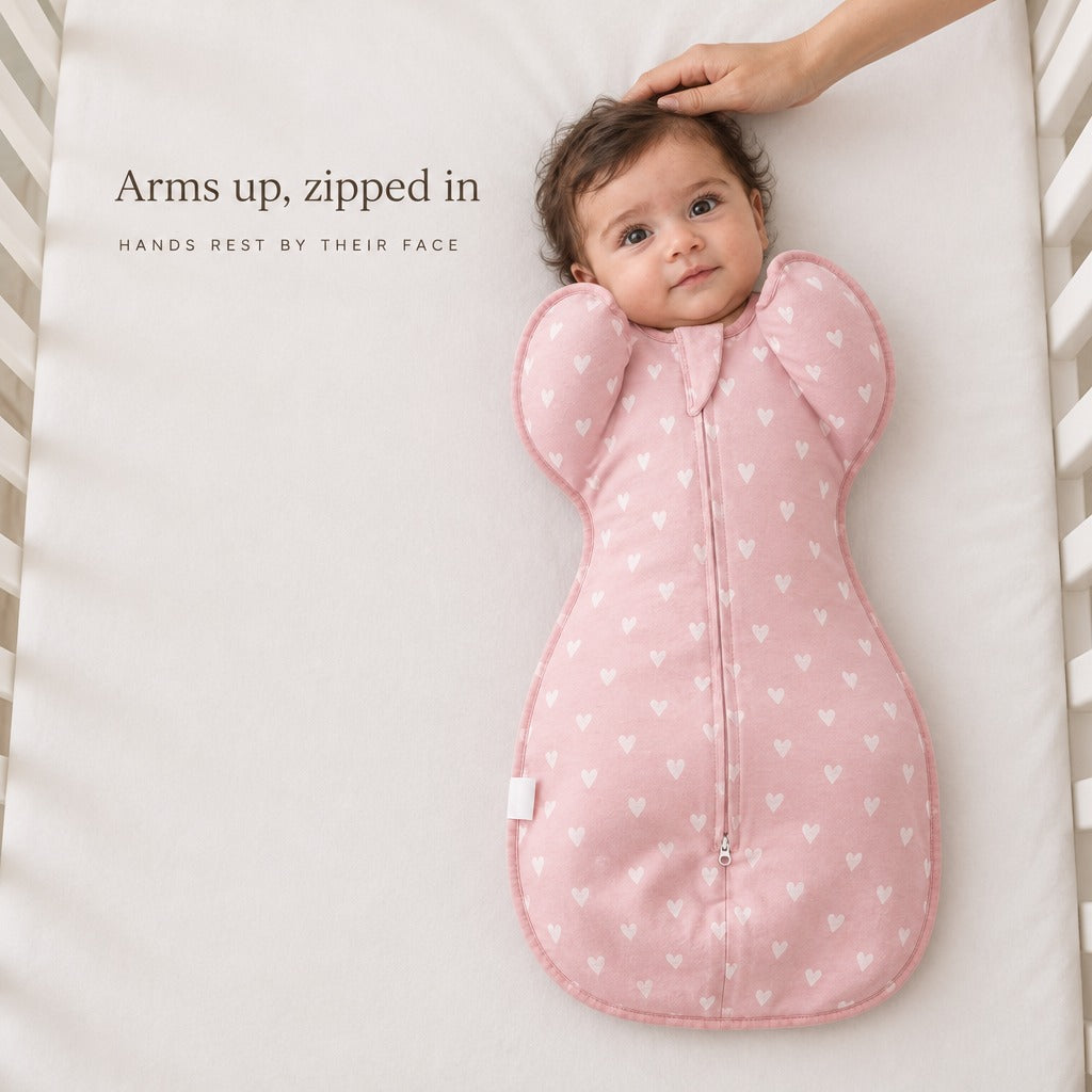 Awake newborn in the Peach Pink Hearts Petal Swaddle with arms up — Arms up, zipped in