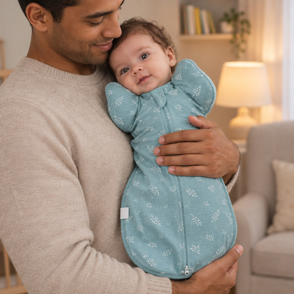 Father holding his awake newborn in the Green Leaves Petal Swaddle