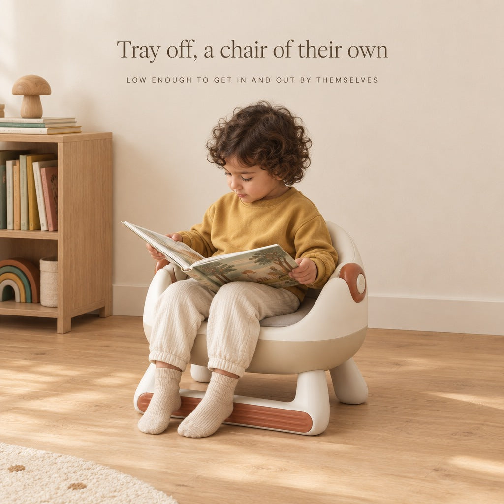 Child reading a book in the toddler low chair with the tray removed
