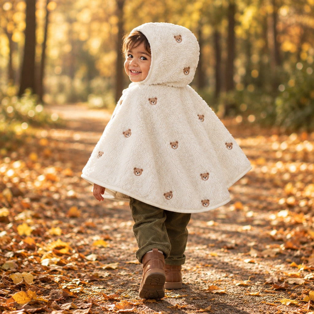 Toddler walking through autumn leaves in The Teddy Mantle, embroidered bears on the back
