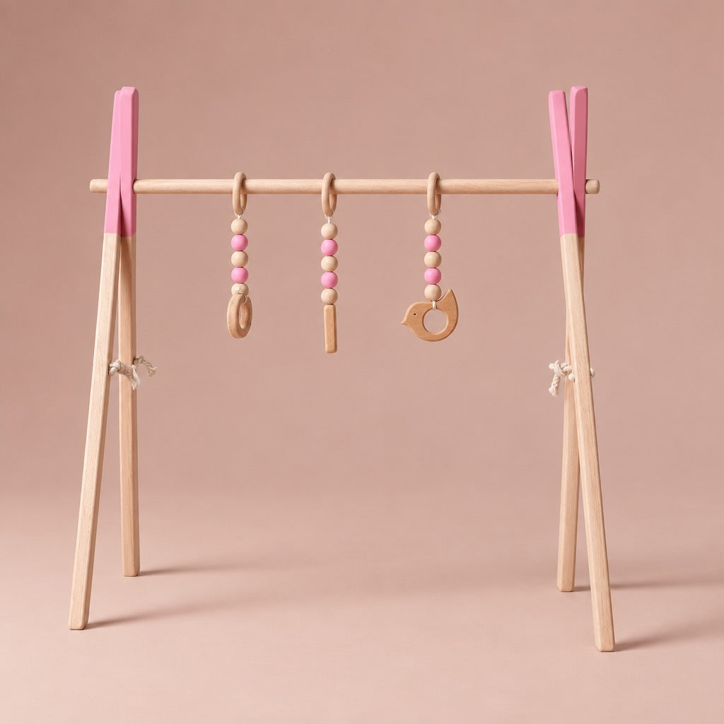 Wooden baby play gym with pink painted tops and three hanging toys